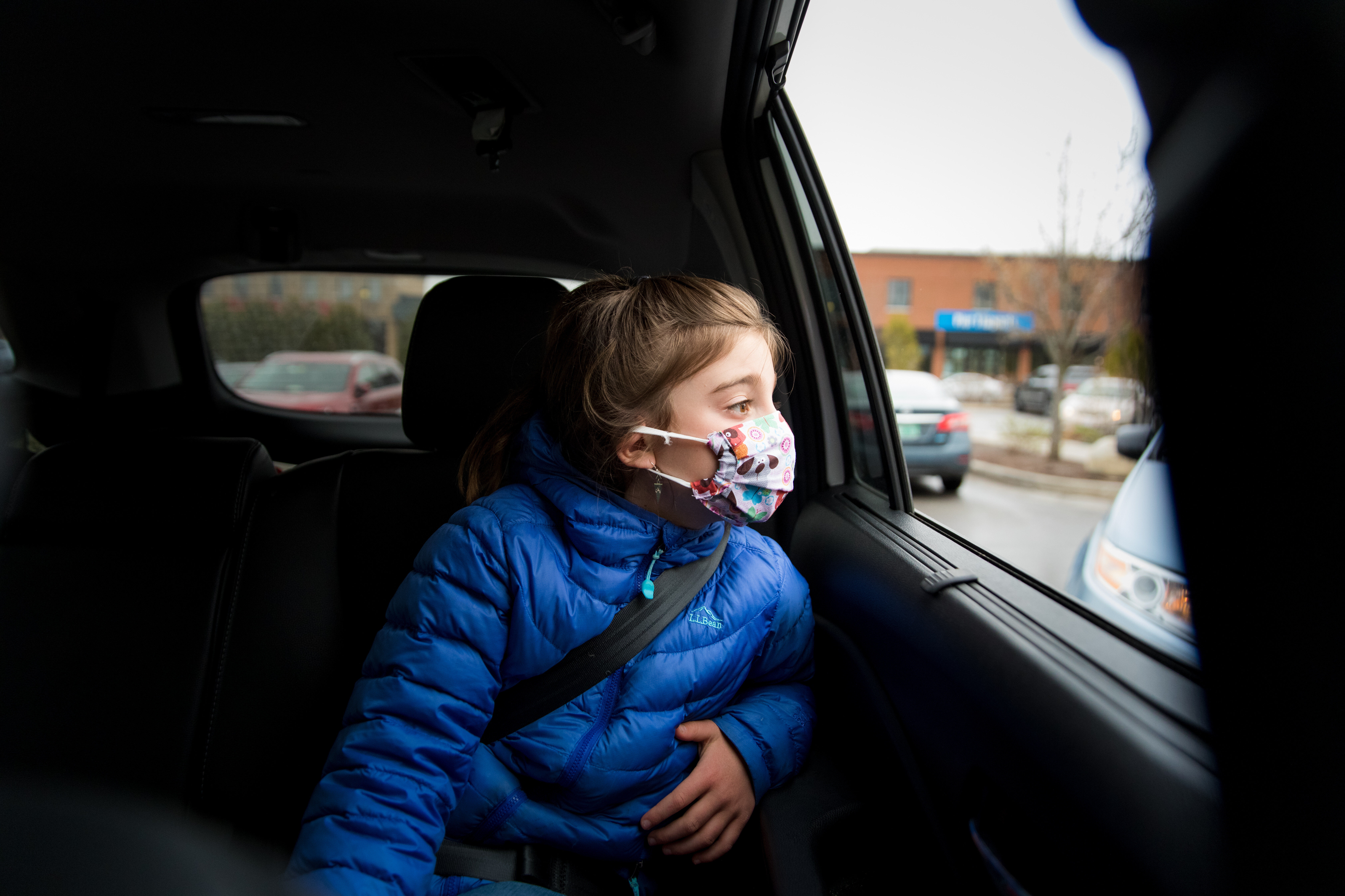 girl in backseat of car with covid mask